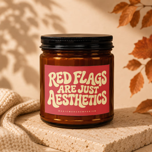 Amber candle in glass jar with red label saying "Red Flags Are Just Aesthetics".