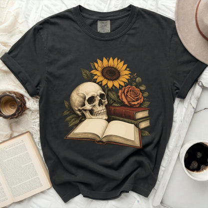Skull with sunflower, rose, and open book graphic on a charcoal t-shirt.