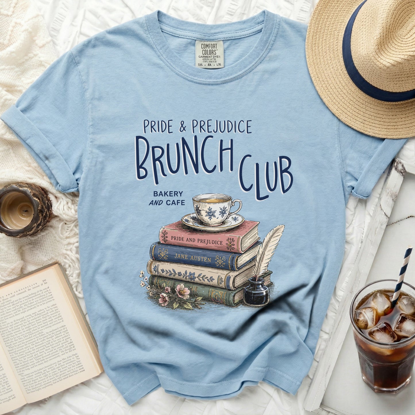Blue t-shirt with "Pride & Prejudice Brunch Club" graphic and stack of books.