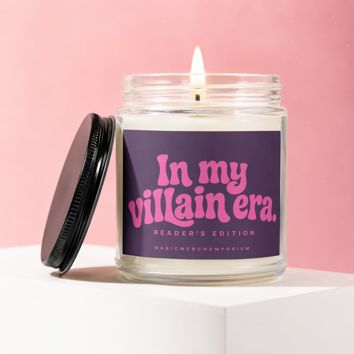 Lit candle in glass jar with purple label reading "In my villain era. Reader's Edition."