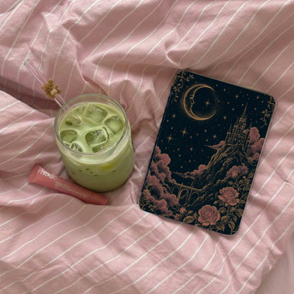 Aesthetic book cover with castle, moon, and roses, next to a green drink and lip balm.