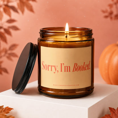 Amber jar candle with lit wick, "Sorry, I'm Booked" text, and black lid.
