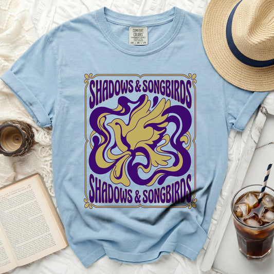 Light blue t-shirt with "Shadows & Songbirds" text and bird graphic.