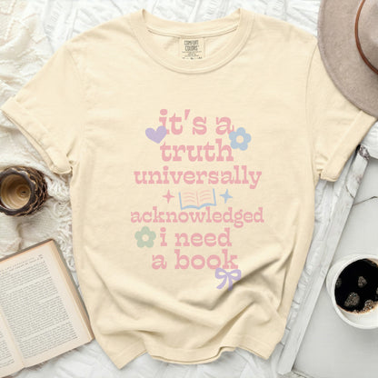 Cream t-shirt with pink text saying "it's a truth universally acknowledged i need a book".