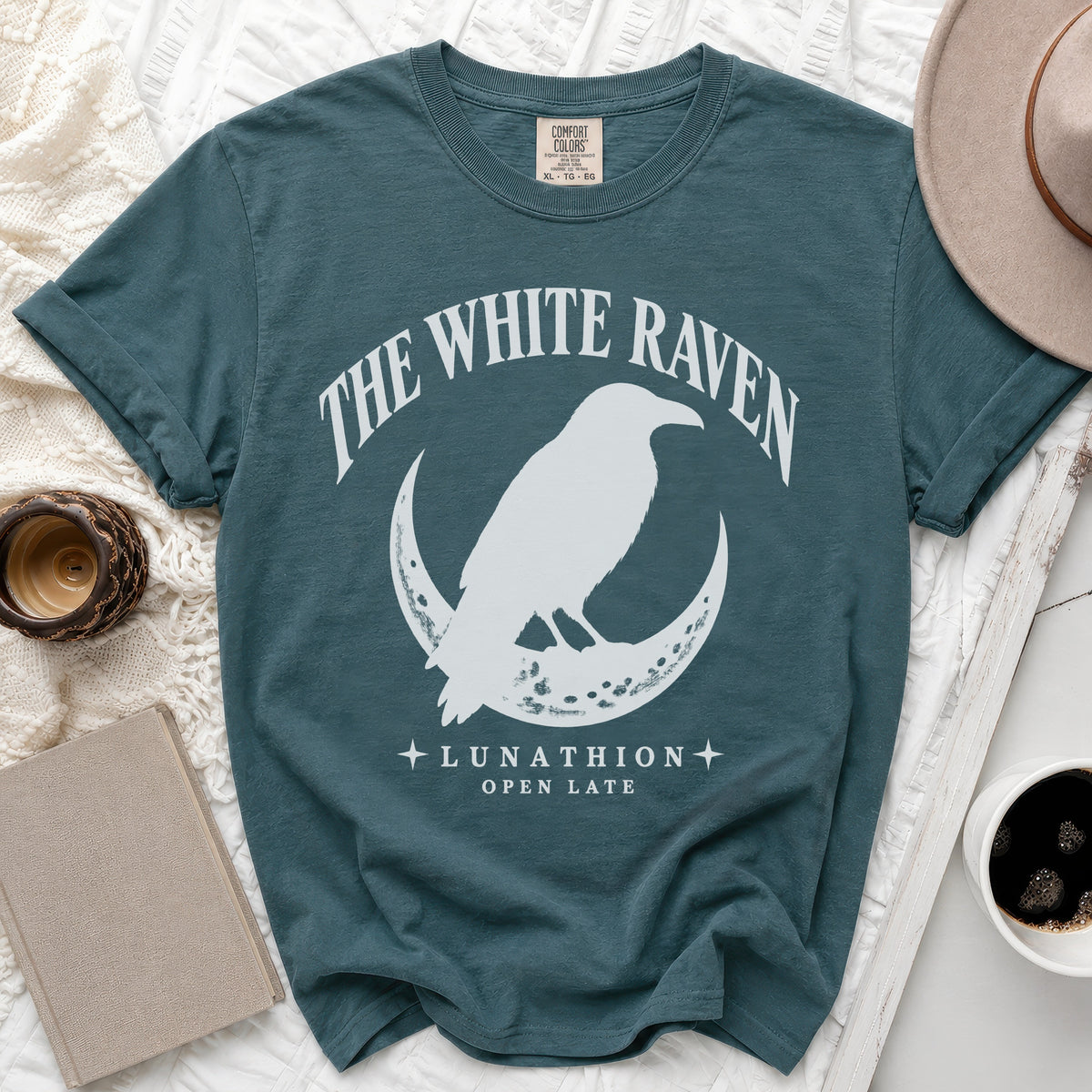 Teal t-shirt with white raven on crescent moon graphic and text.