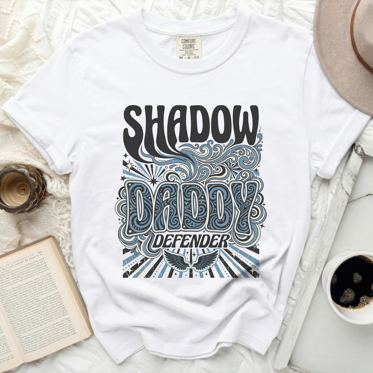 White t-shirt with "SHADOW DADDY DEFENDER" graphic and wings.