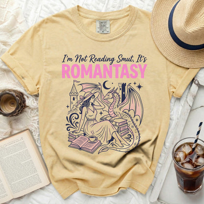 Yellow t-shirt with "I'm Not Reading Smut, It's ROMANTASY" text and a woman with a dragon.