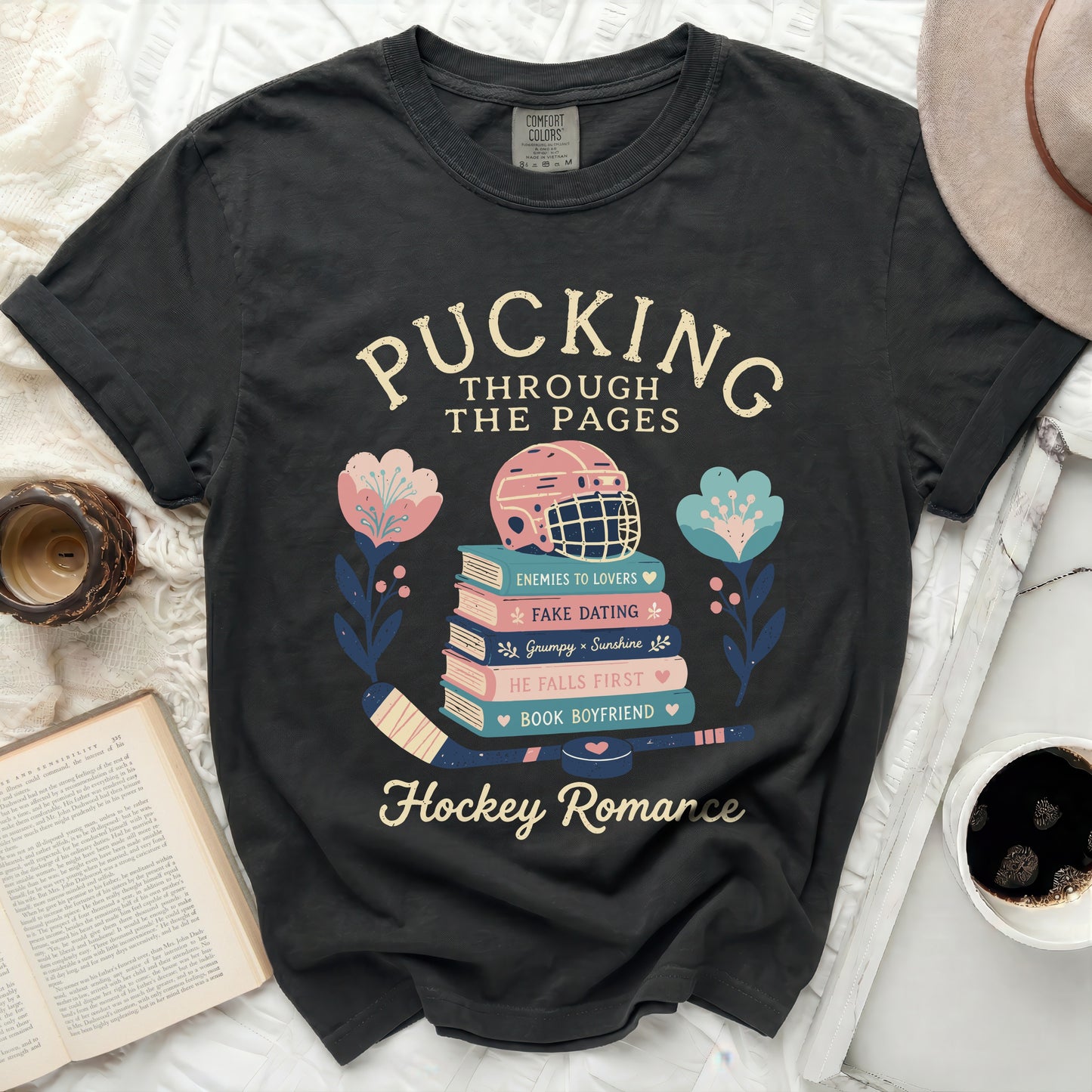T-shirt with "Pucking Through The Pages" text and hockey romance book stack graphic.