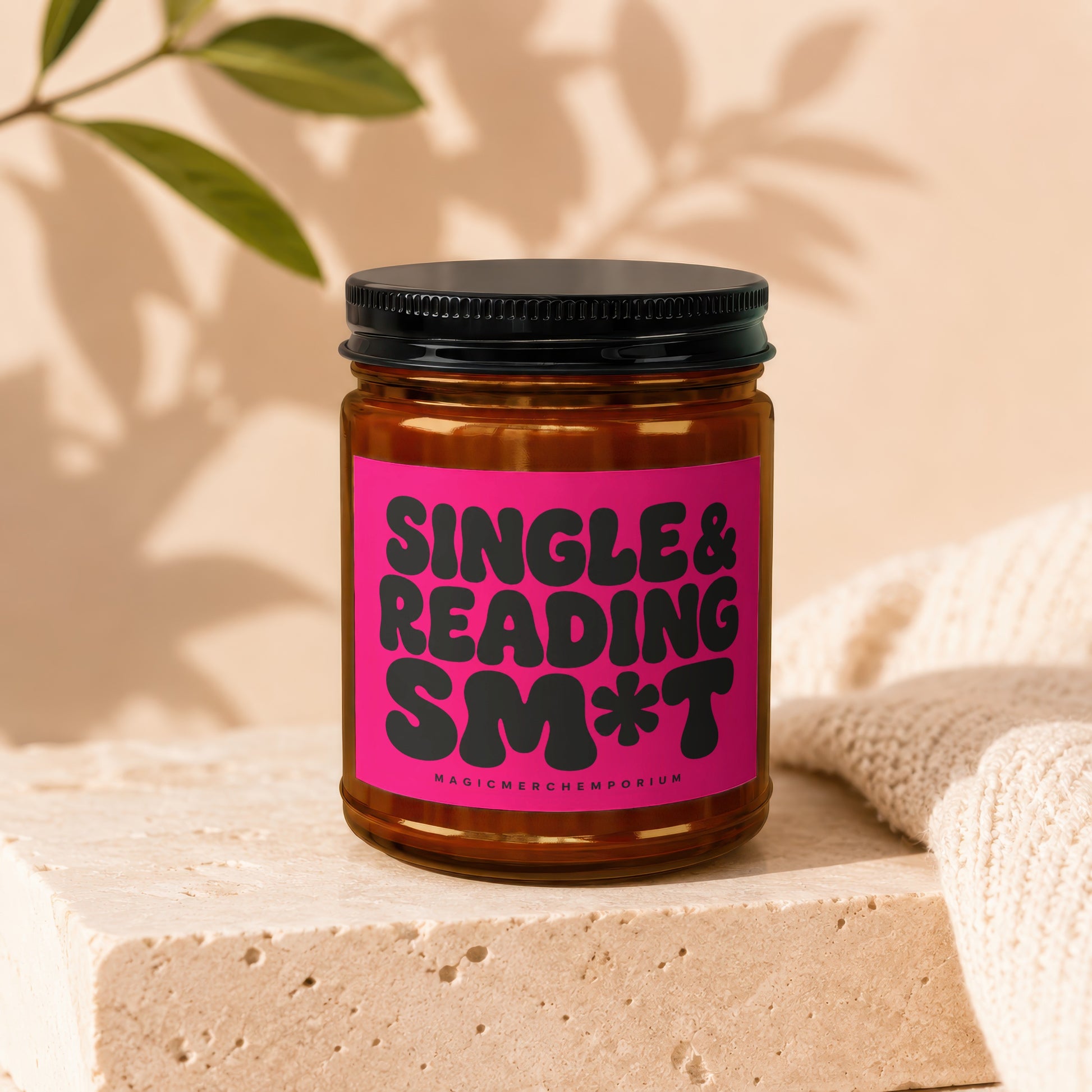 Amber jar candle with pink label reading "SINGLE & READING SM*T".
