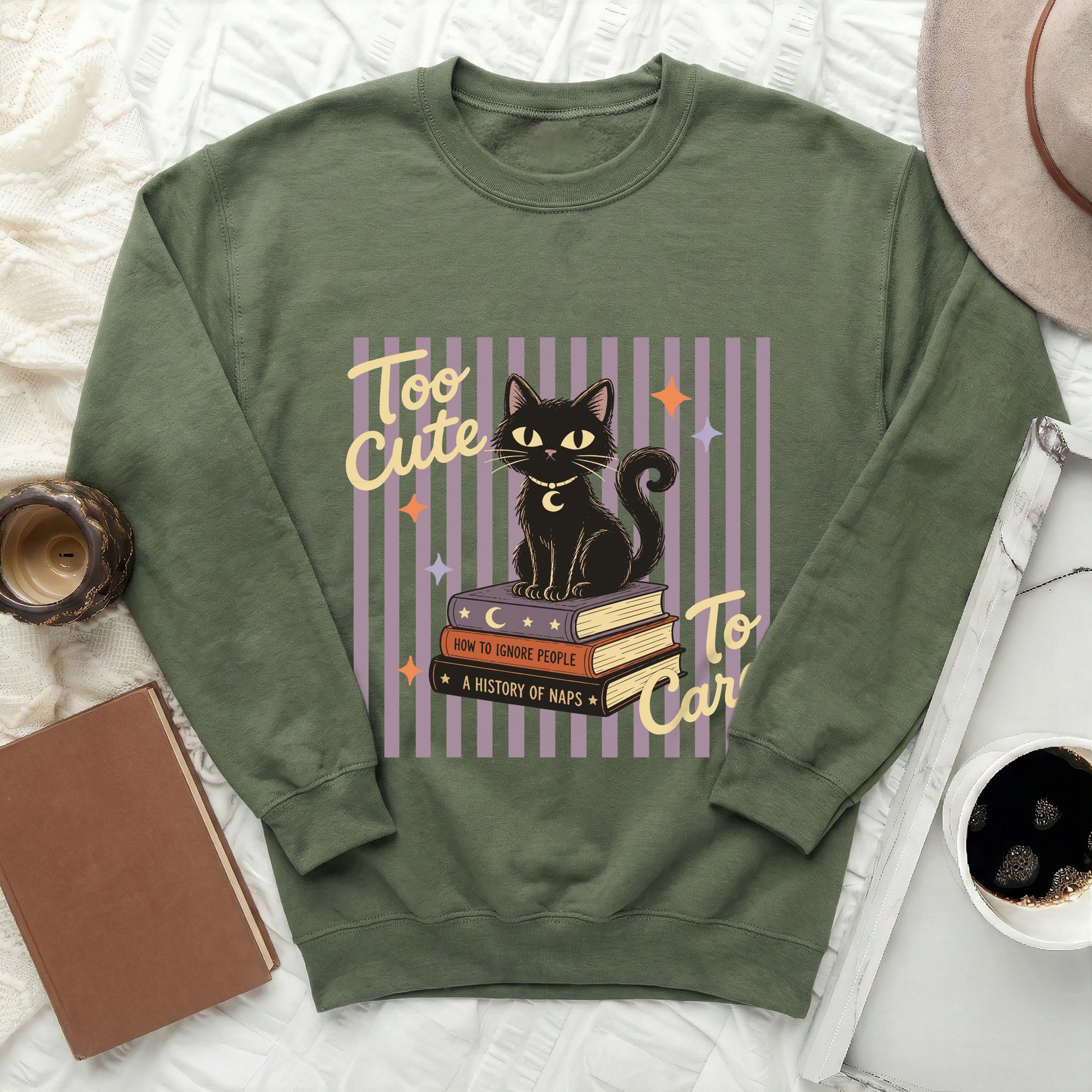 Green sweatshirt with black cat on books graphic reading "Too Cute".