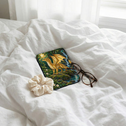 Case with golden dragon and waterfall art, scrunchie, and glasses on white sheets.