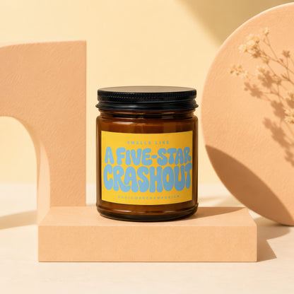 Amber jar candle with yellow label reading "A Five-Star Crashout"