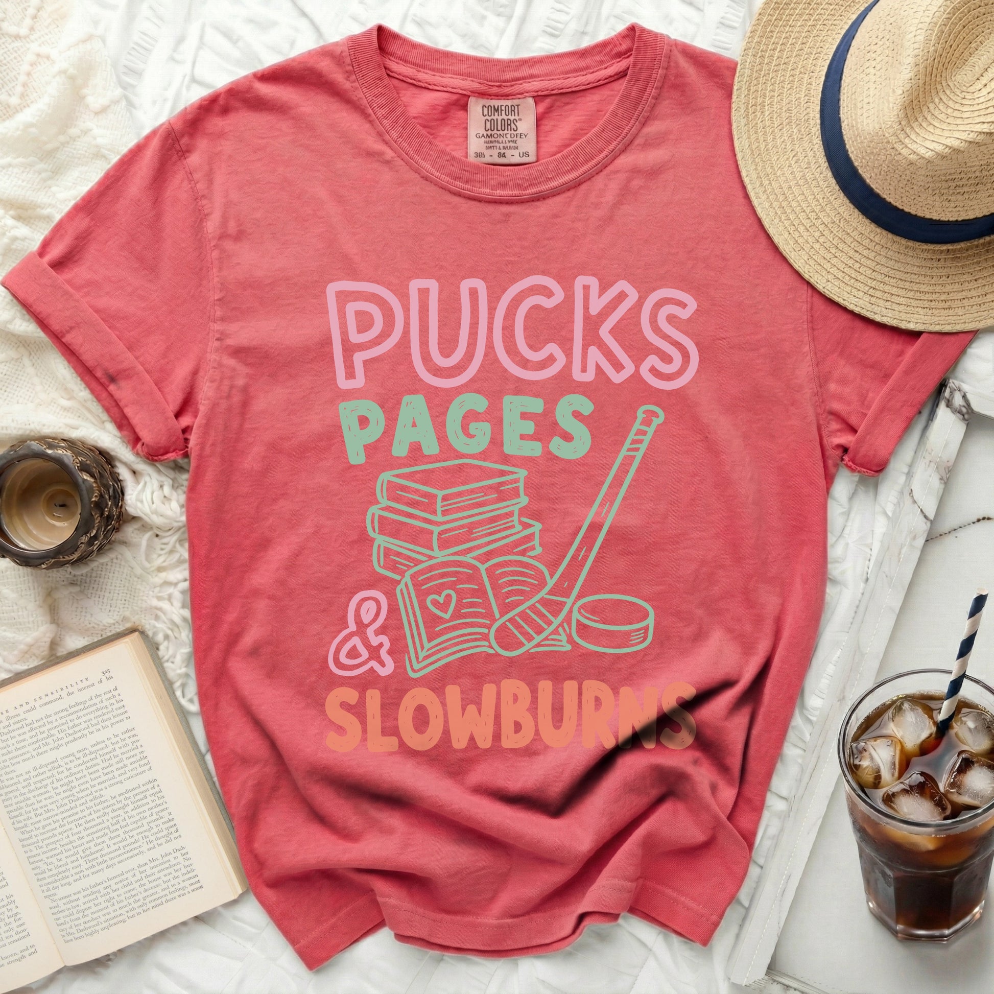 Coral t-shirt with "Pucks, Pages & Slowburn" text and hockey stick.