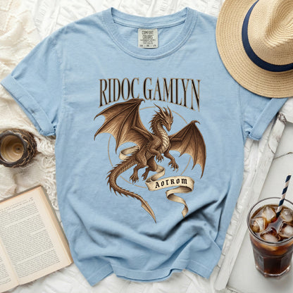 Light blue t-shirt with a brown dragon graphic and text "RIDOC GAMLYN AOTROM".