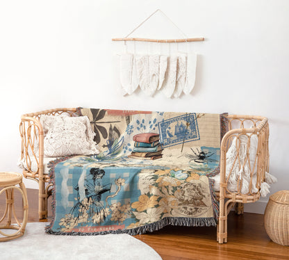 a cozy living room with a wicker sofa adorned with a colorful throw blanket that has a floral and bird motif. The blanket is draped over the sofa, creating a warm and inviting atmosphere. Above the sofa, there is a hanging decoration made of white feathers, adding a touch of elegance to the room. The room also includes a small table and a woven basket, contributing to the overall rustic and charming aesthetic.
