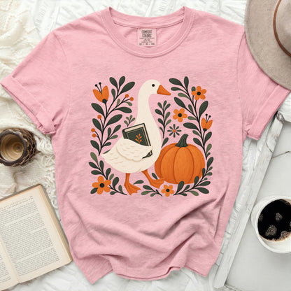 Pink t-shirt with a white goose holding a book and a pumpkin.