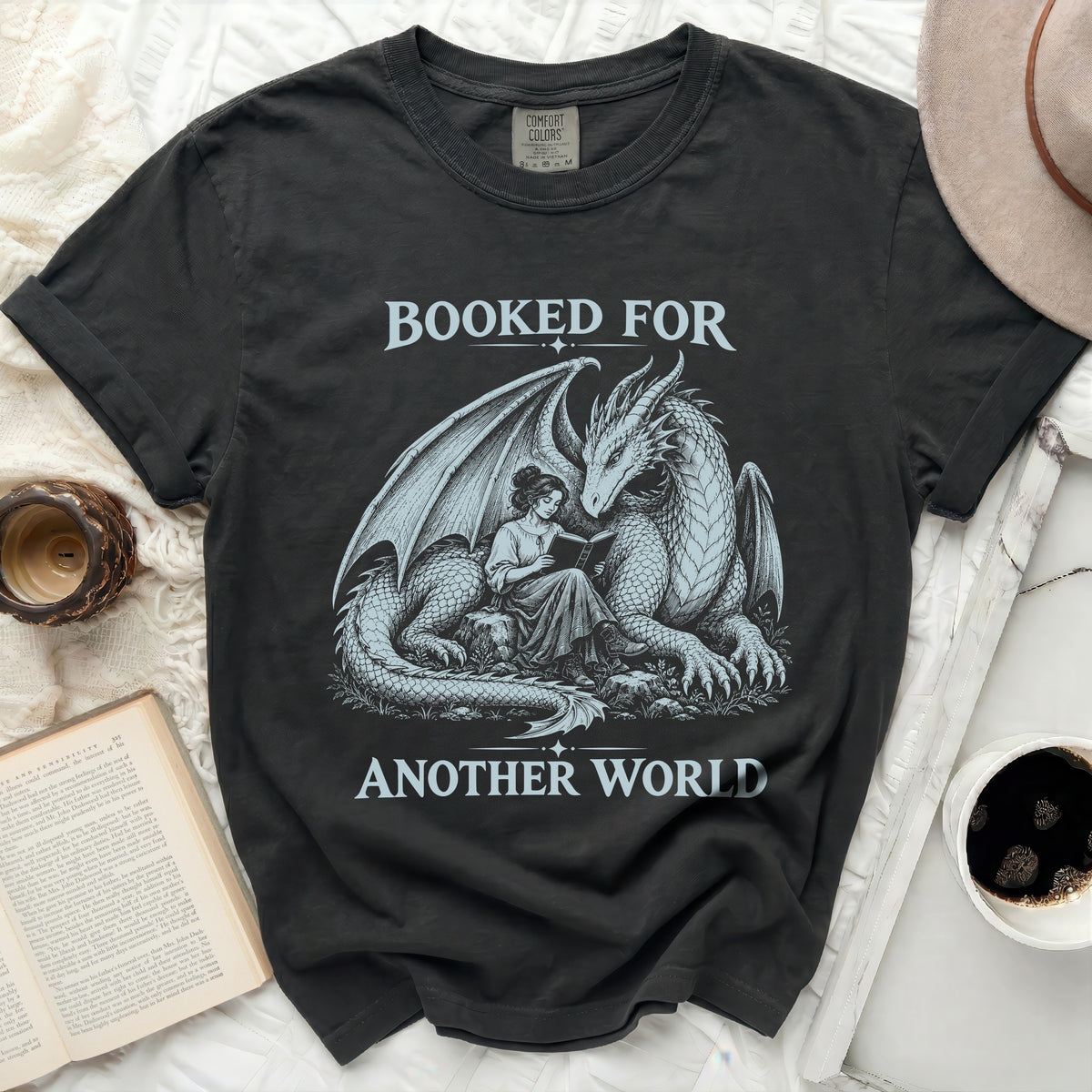 Black t-shirt with dragon and woman reading graphic, "Booked For Another World" text.