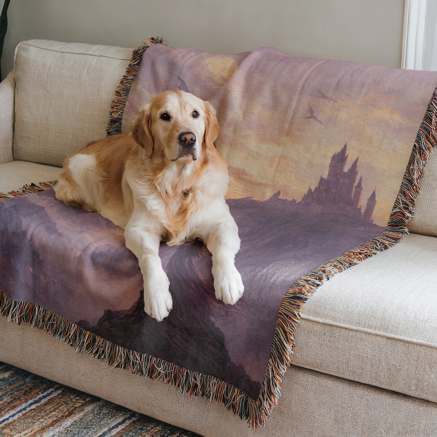 A golden retriever dog is lying on a couch with a purple blanket featuring a castle design.