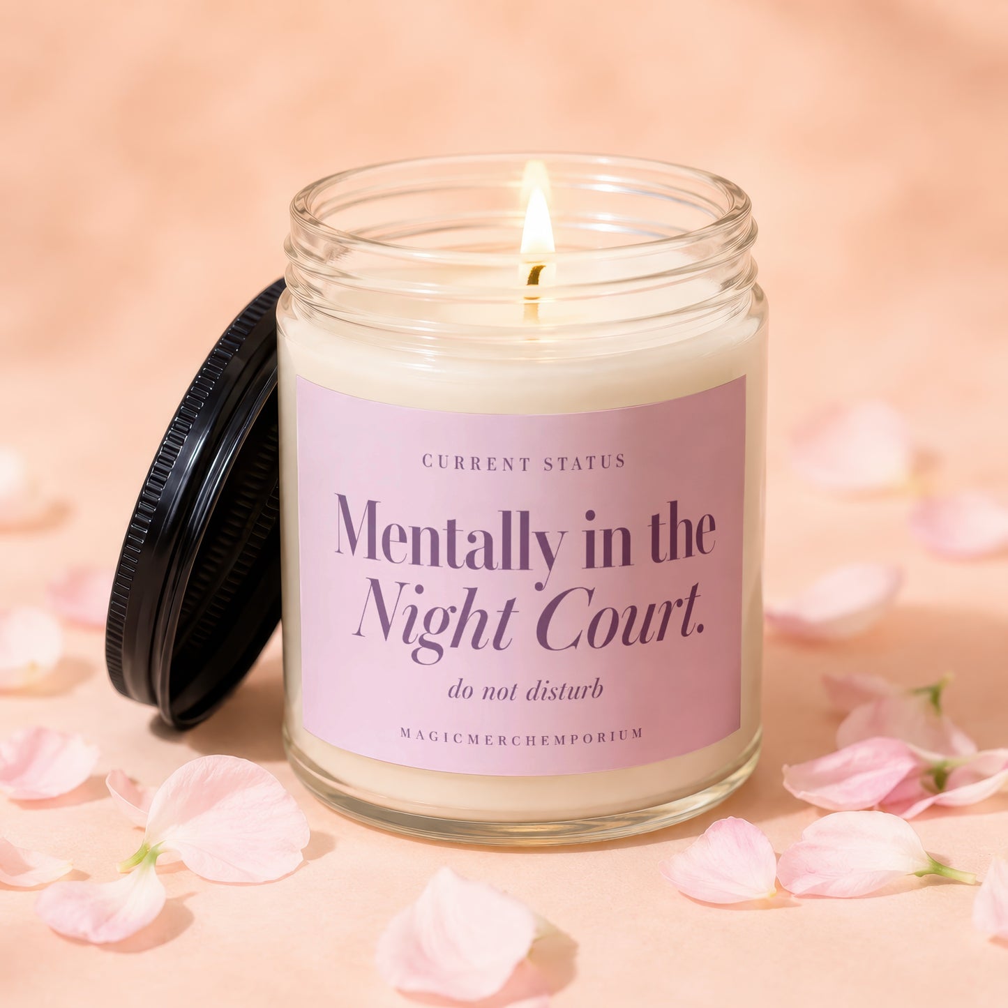 A lit soy candle in a glass jar featuring a pink label with purple text.