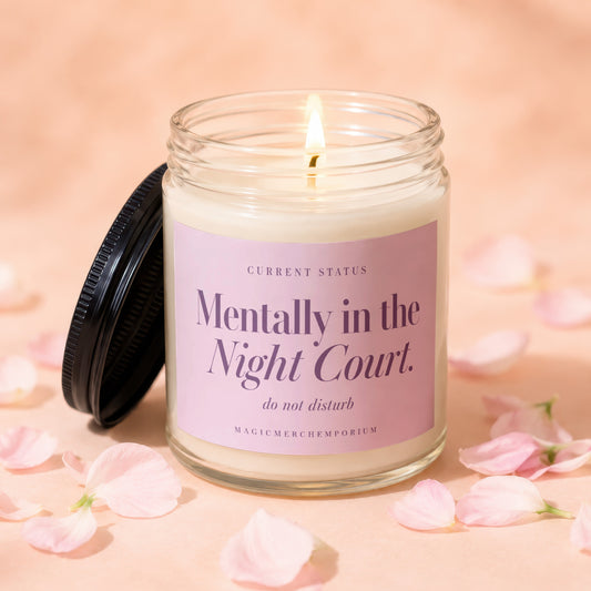 A lit soy candle in a glass jar featuring a pink label with purple text.