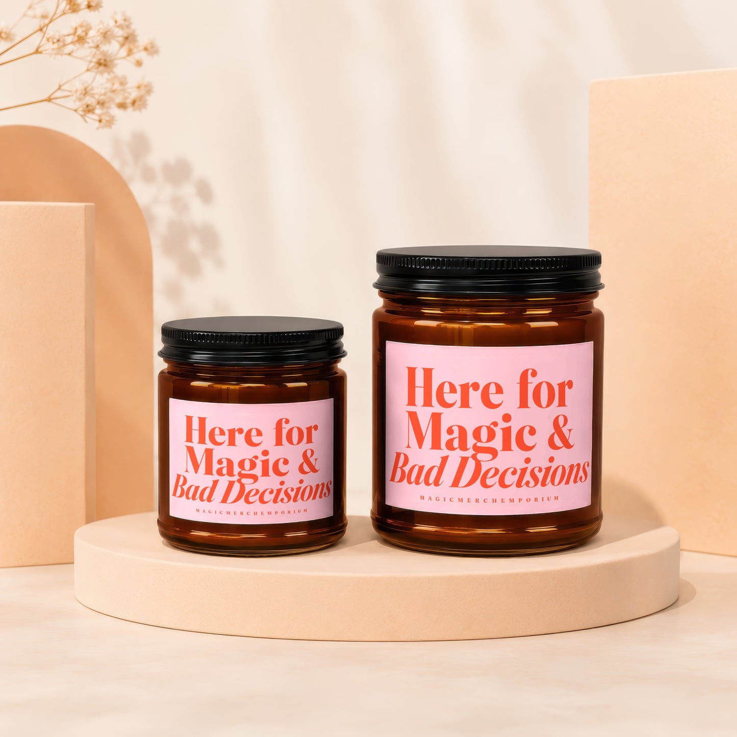 Two amber glass candles with pink labels reading "Here for Magic & Bad Decisions."