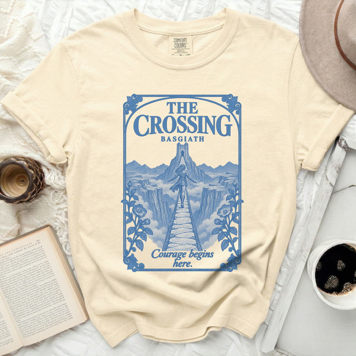 Cream t-shirt with blue graphic of a bridge and castle, reading "The Crossing Basgiath Courage begins here."