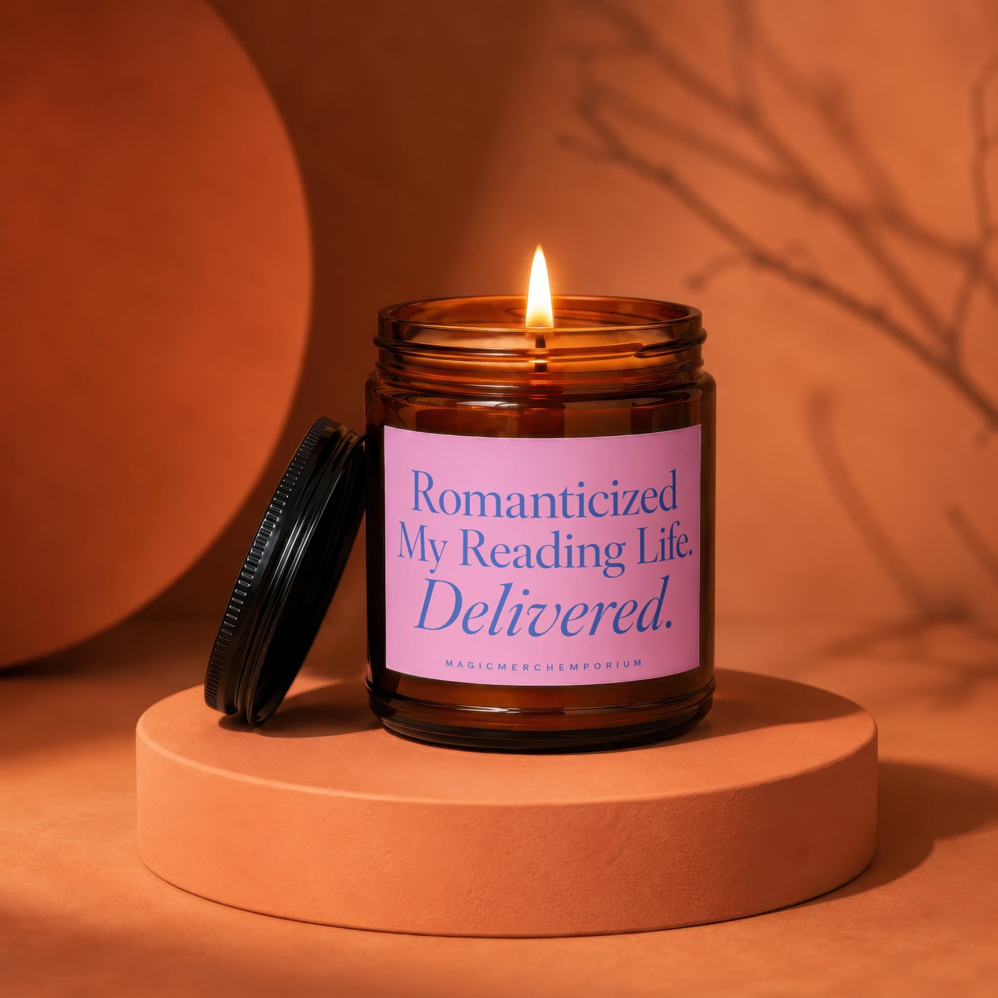 Amber jar candle with lit flame, pink label reading "Romanticized My Reading Life. Delivered."