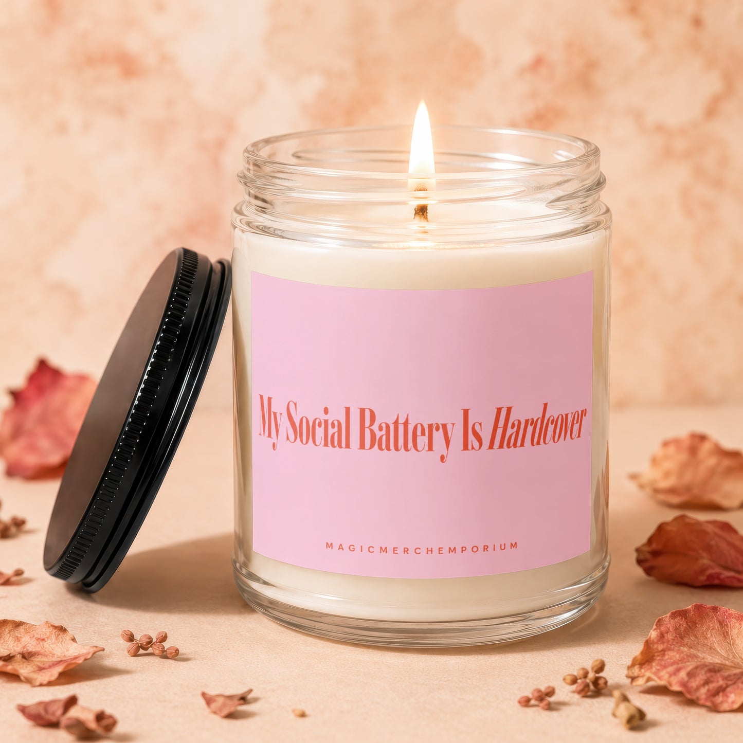 Jar candle with a pink label reading "My Social Battery Is Hardcover" and "MAGICMERCH`EMPORIUM"