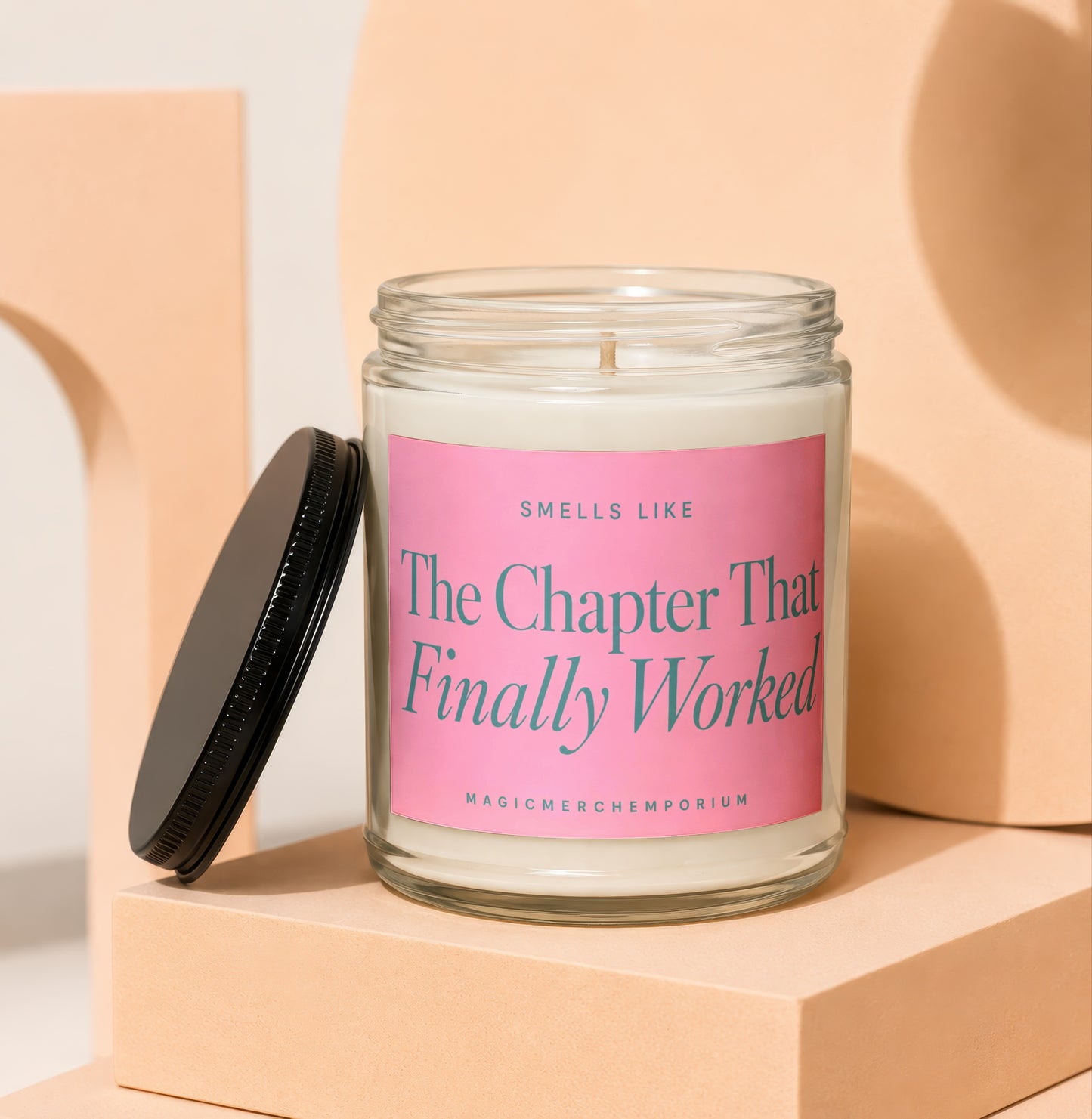 Glass candle with pink label that reads "The Chapter That Finally Worked"