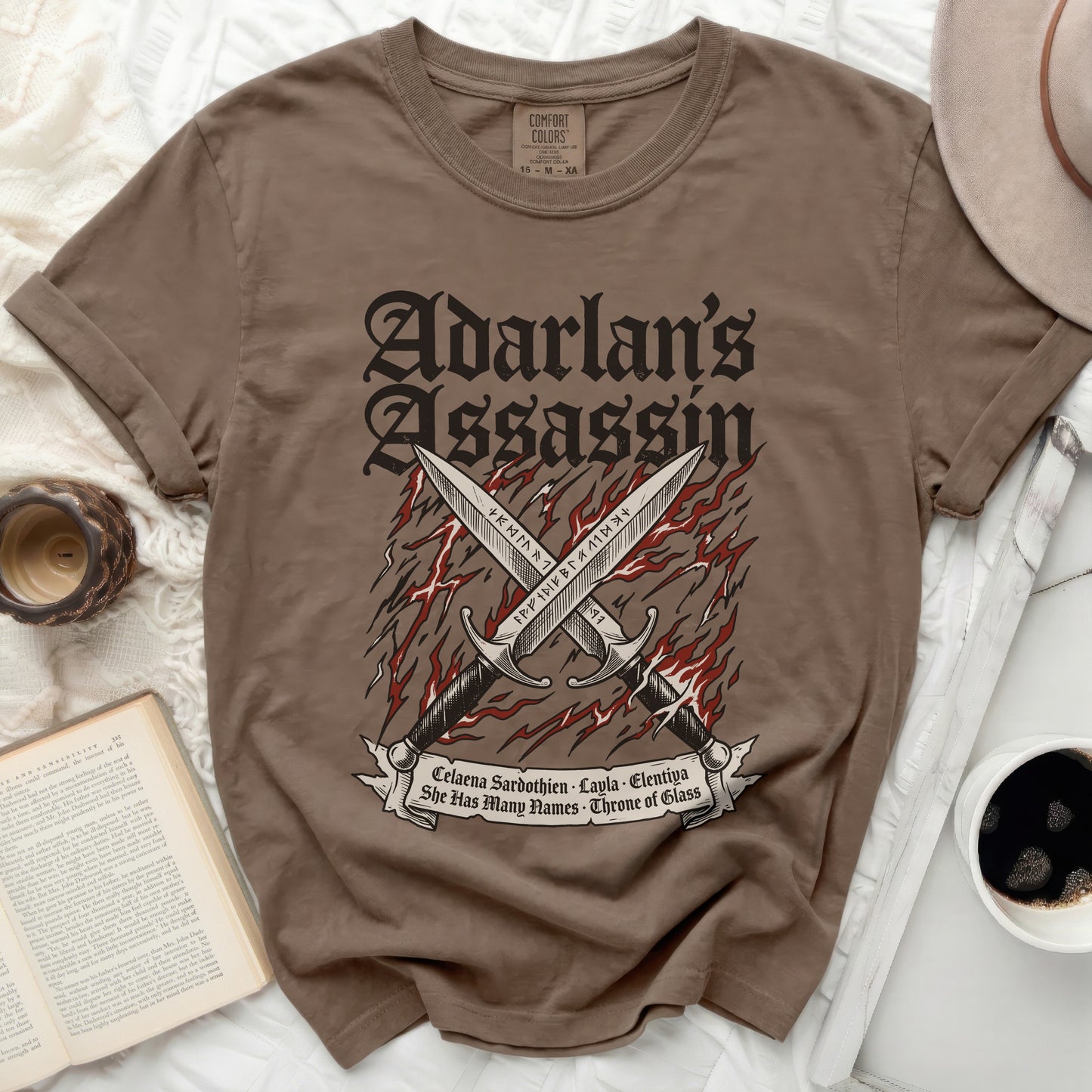 Brown t-shirt with "Adarlan's Assassin" and crossed swords graphic.
