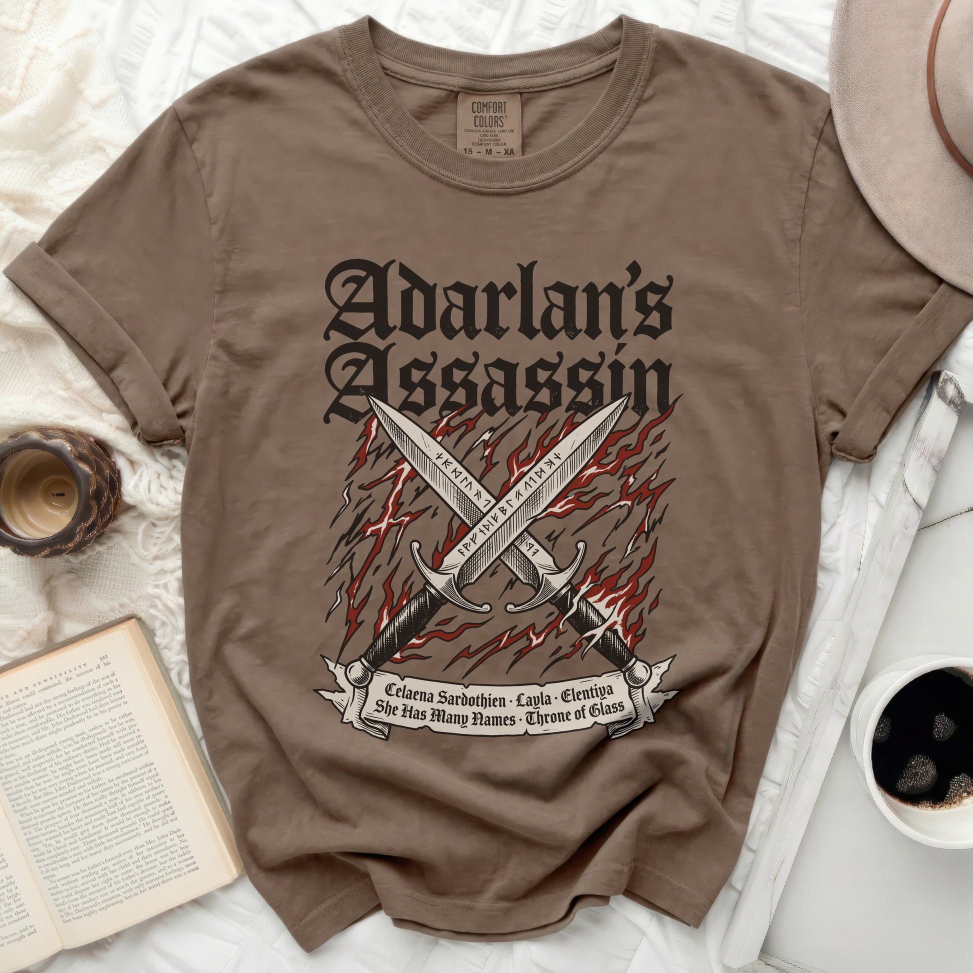 Brown t-shirt with "Adarlan's Assassin" and crossed swords graphic.