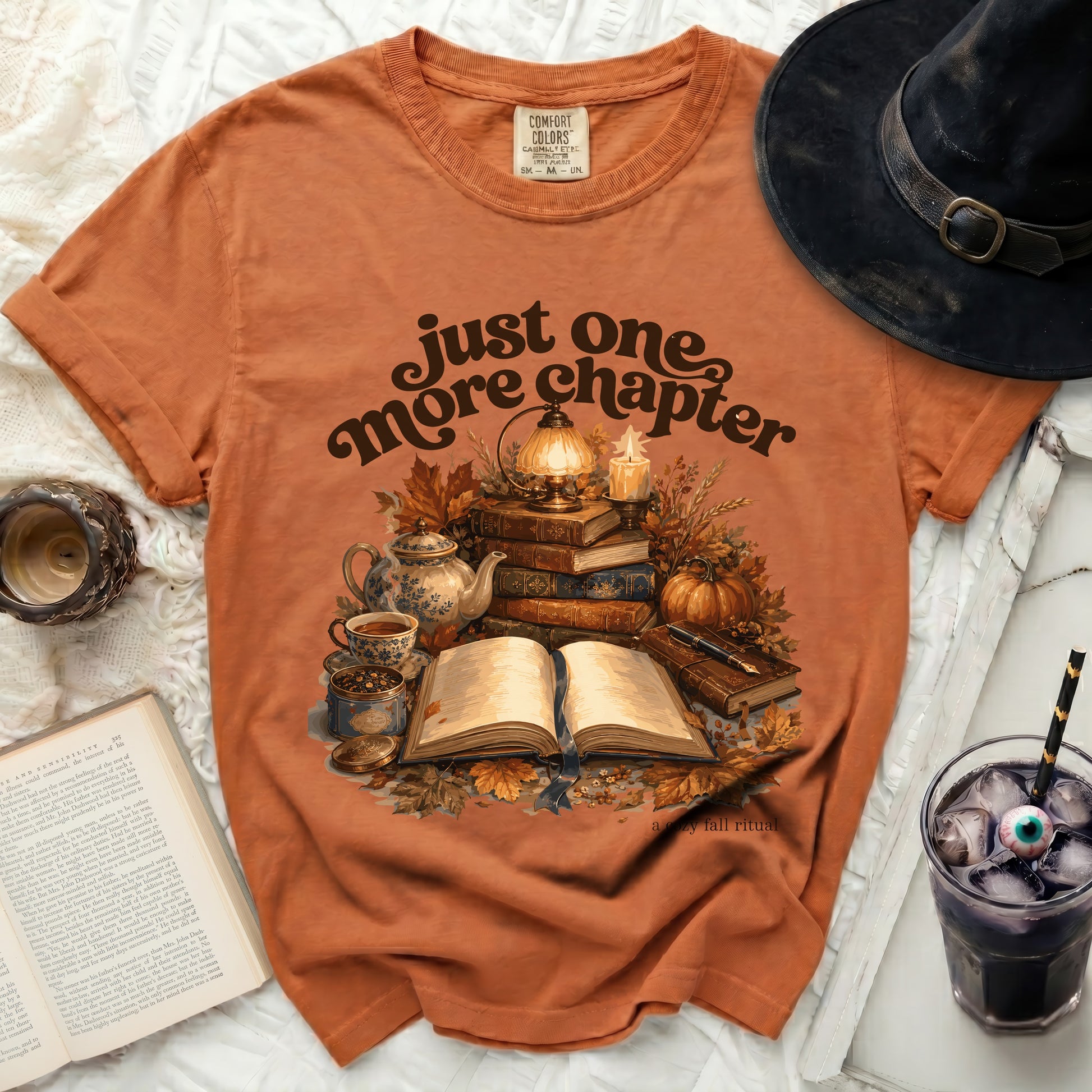 Orange t-shirt with "Just One More Chapter" and fall reading scene.