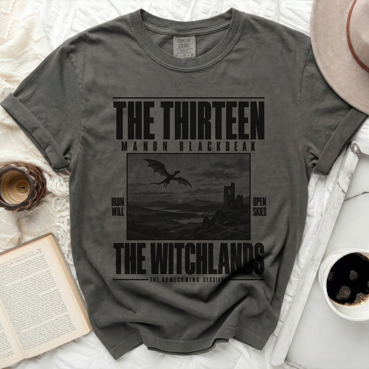 Gray t-shirt with "The Thirteen Manon Blackbeak The Witchlands" text and dragon graphic.