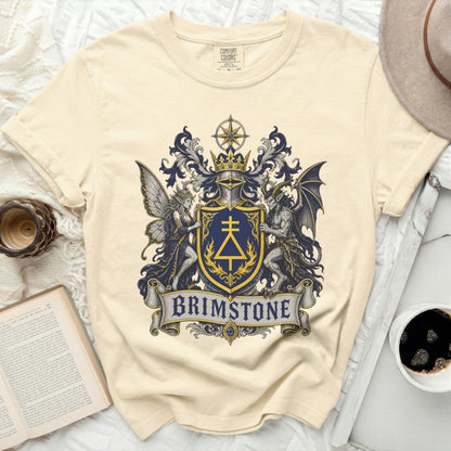 Cream t-shirt with a blue crest featuring a dragon, fairy, and the word "BRIMSTONE".
