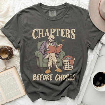 Graphic tee with skeleton reading a book and text "CHAPTERS BEFORE CHORES".