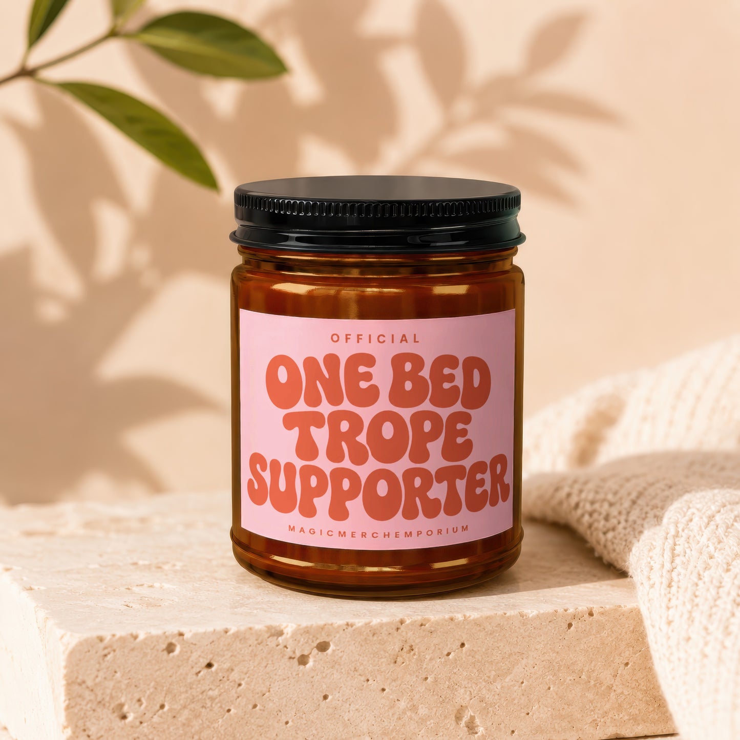 Amber glass candle with pink label reading "Official One Bed Trope Supporter".