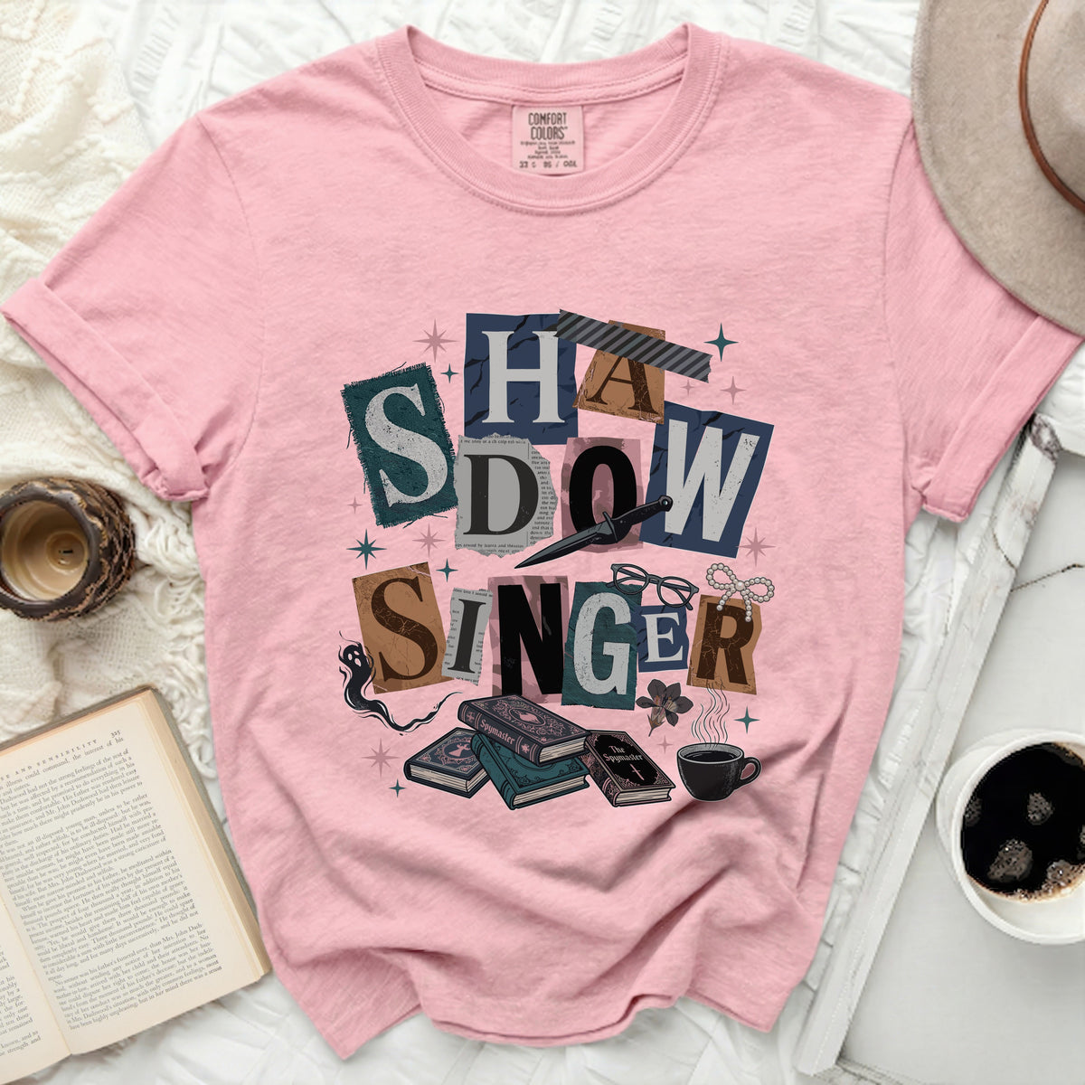 Pink t-shirt with "SHADOW SINGER" collage graphic and books.