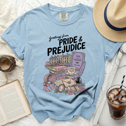 Light blue t-shirt with "Greetings from Pride & Prejudice" and illustrated books and homestead.