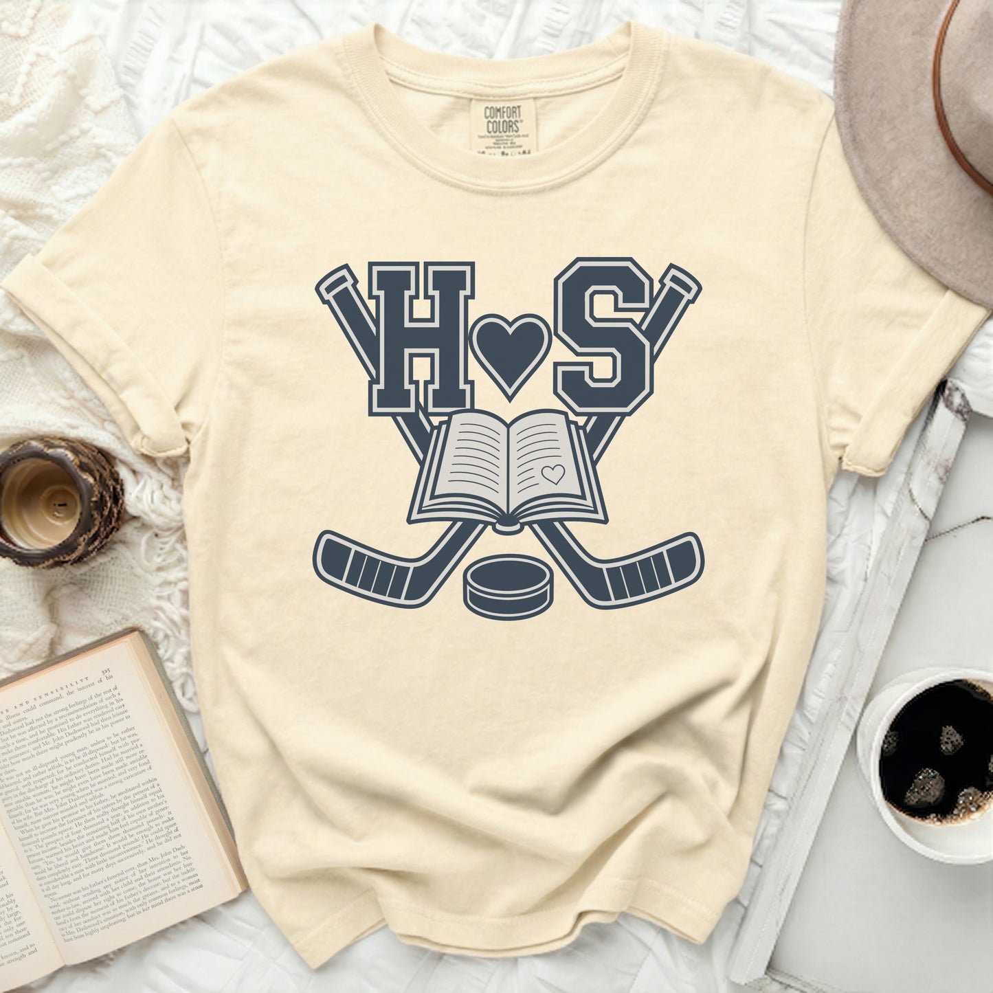 Cream t-shirt with "H S" and crossed hockey sticks over an open book.