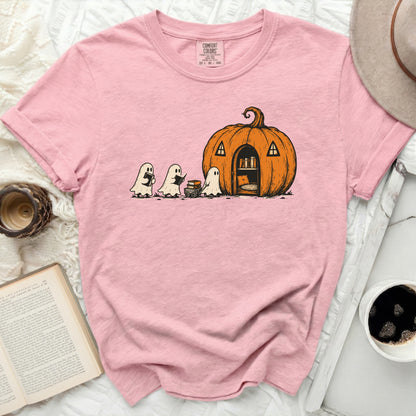 Pink t-shirt with cartoon of ghosts reading books in front of a pumpkin house.