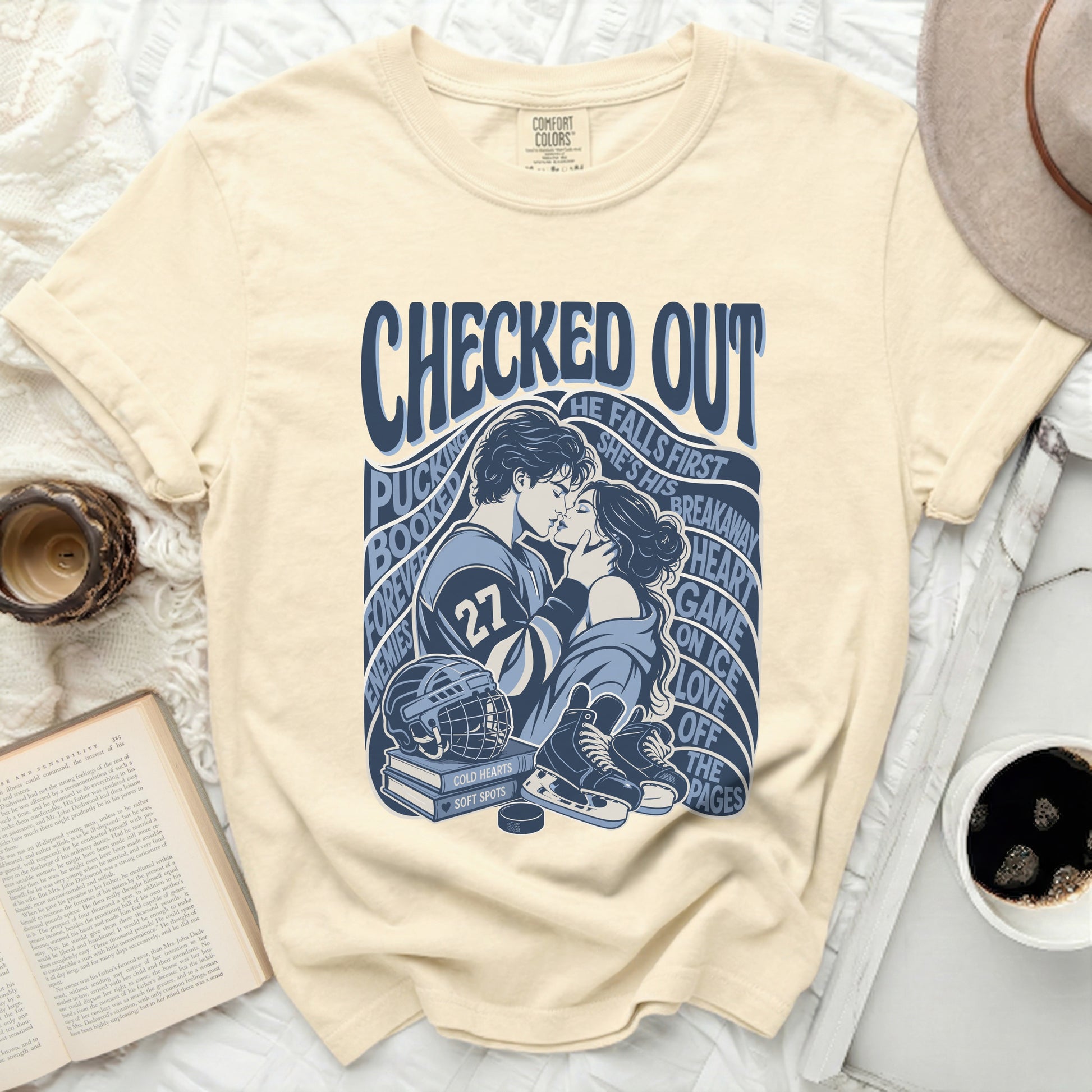 Cream t-shirt with blue text and graphics of hockey players, puck, and skates.