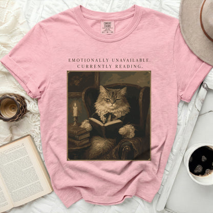 Pink t-shirt with graphic of a cat reading, "Emotionally Unavailable. Currently Reading."
