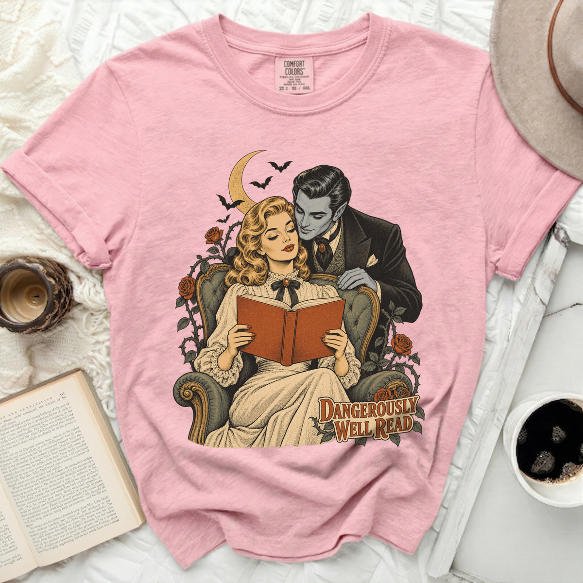 Pink t-shirt with vintage gothic art of a couple reading, "DANGEROUSLY WELL READ" text.