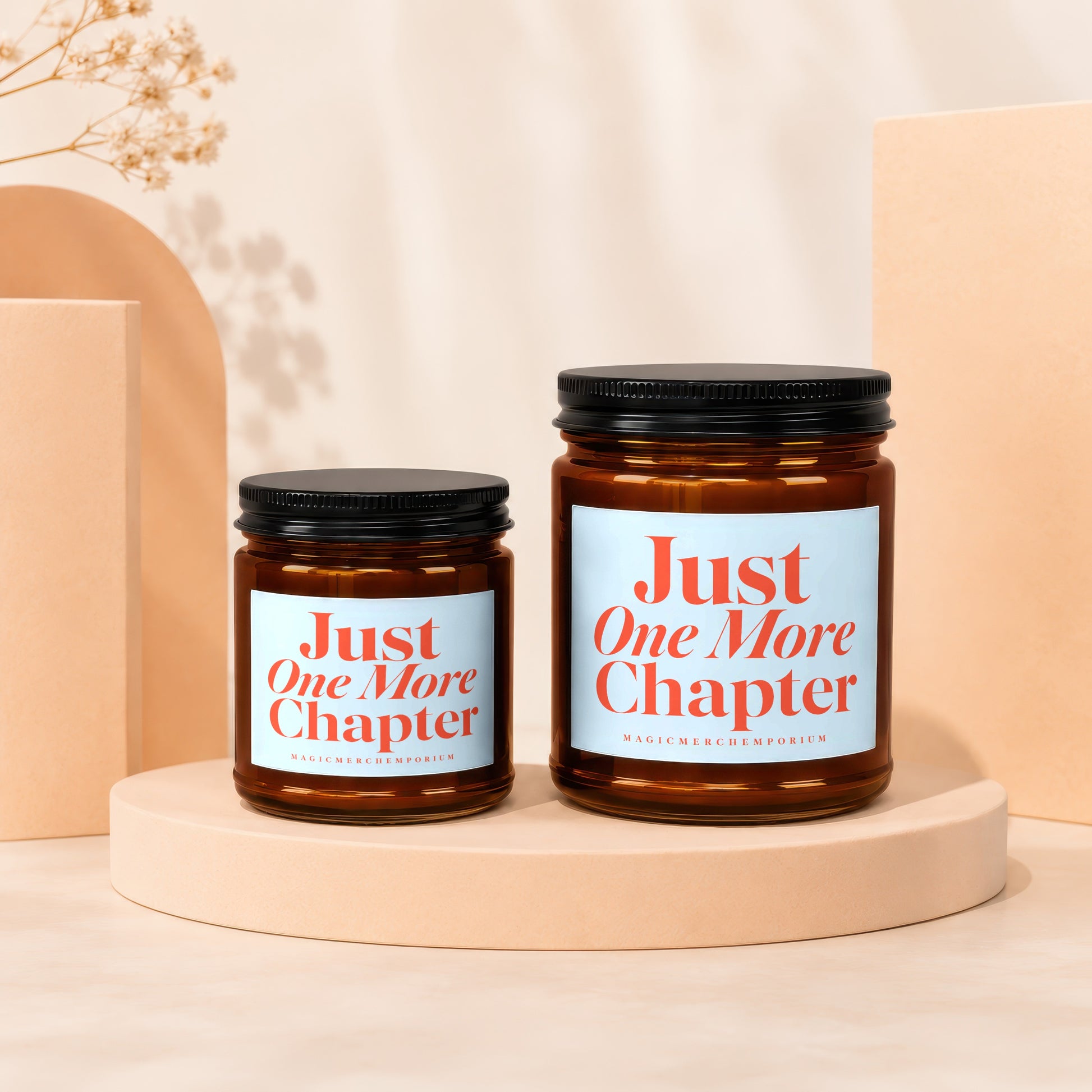 Two amber glass candles with black lids, labeled "Just One More Chapter."