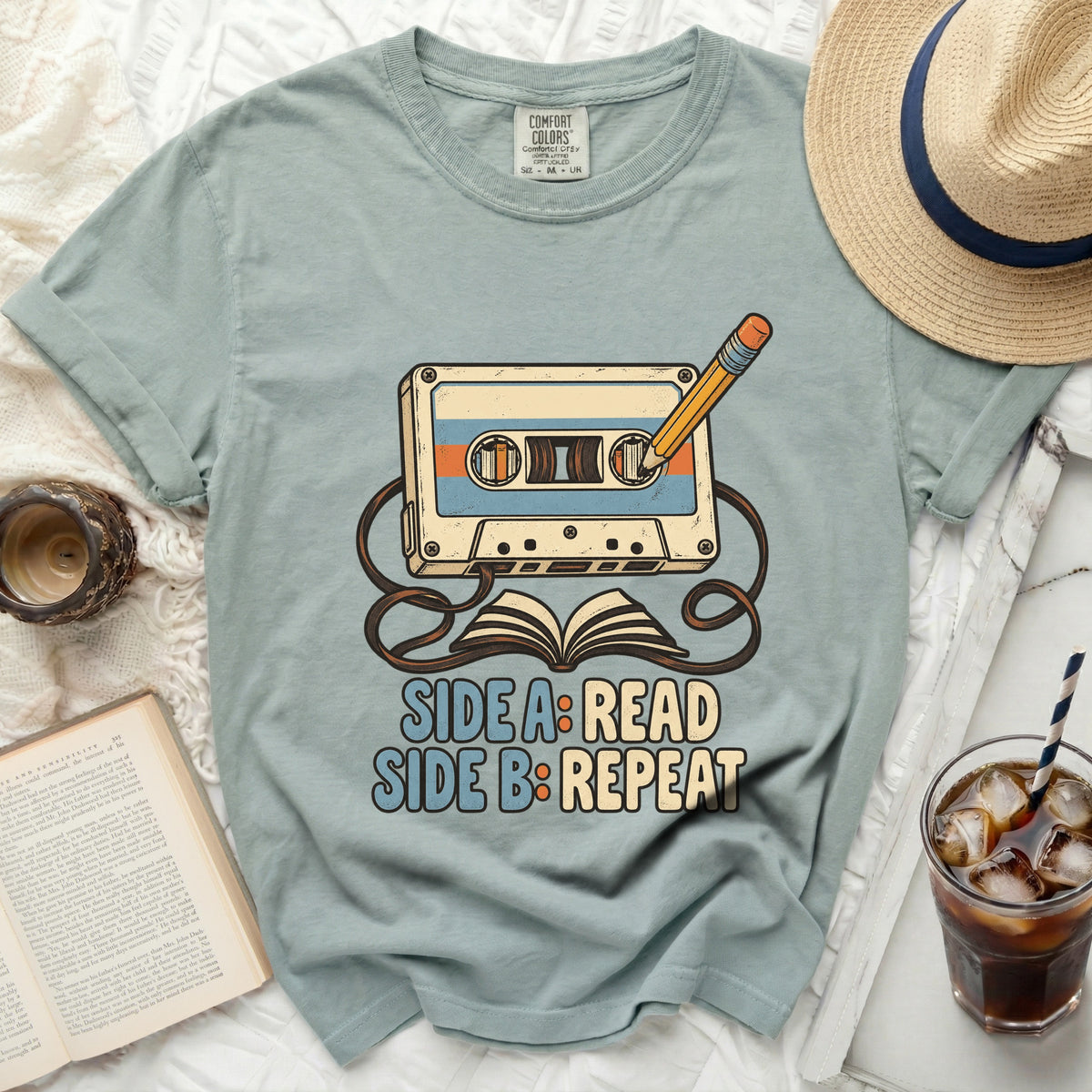 T-shirt with cassette tape, pencil, and open book graphic that says "SIDE A: READ SIDE B: REPEAT".