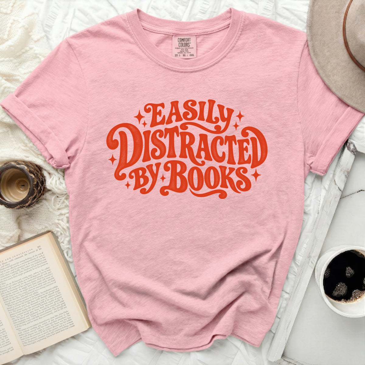 Pink t-shirt with "Easily Distracted by Books" in orange text.