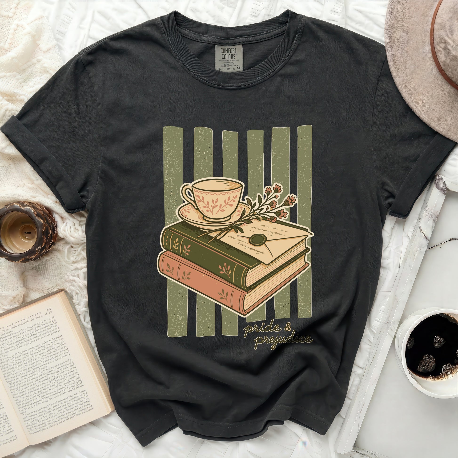 Graphic t-shirt with books, teacup, envelope, and "pride & prejudice" text.