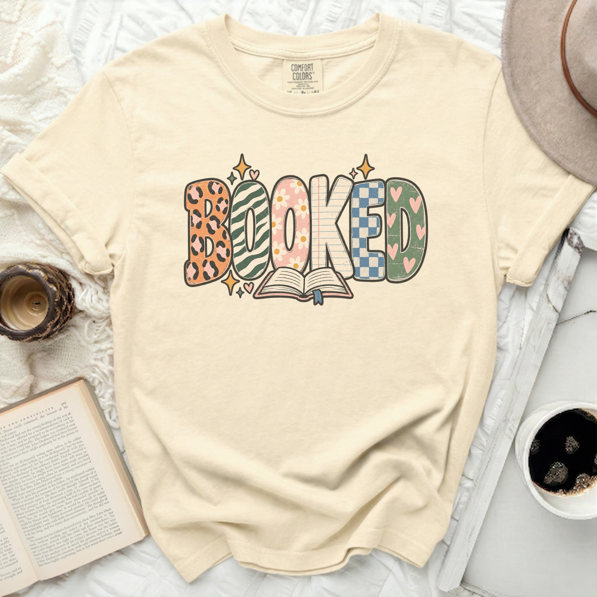 Cream t-shirt with "BOOKED" text and an open book graphic.