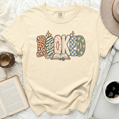 Cream t-shirt with "BOOKED" text and an open book graphic.
