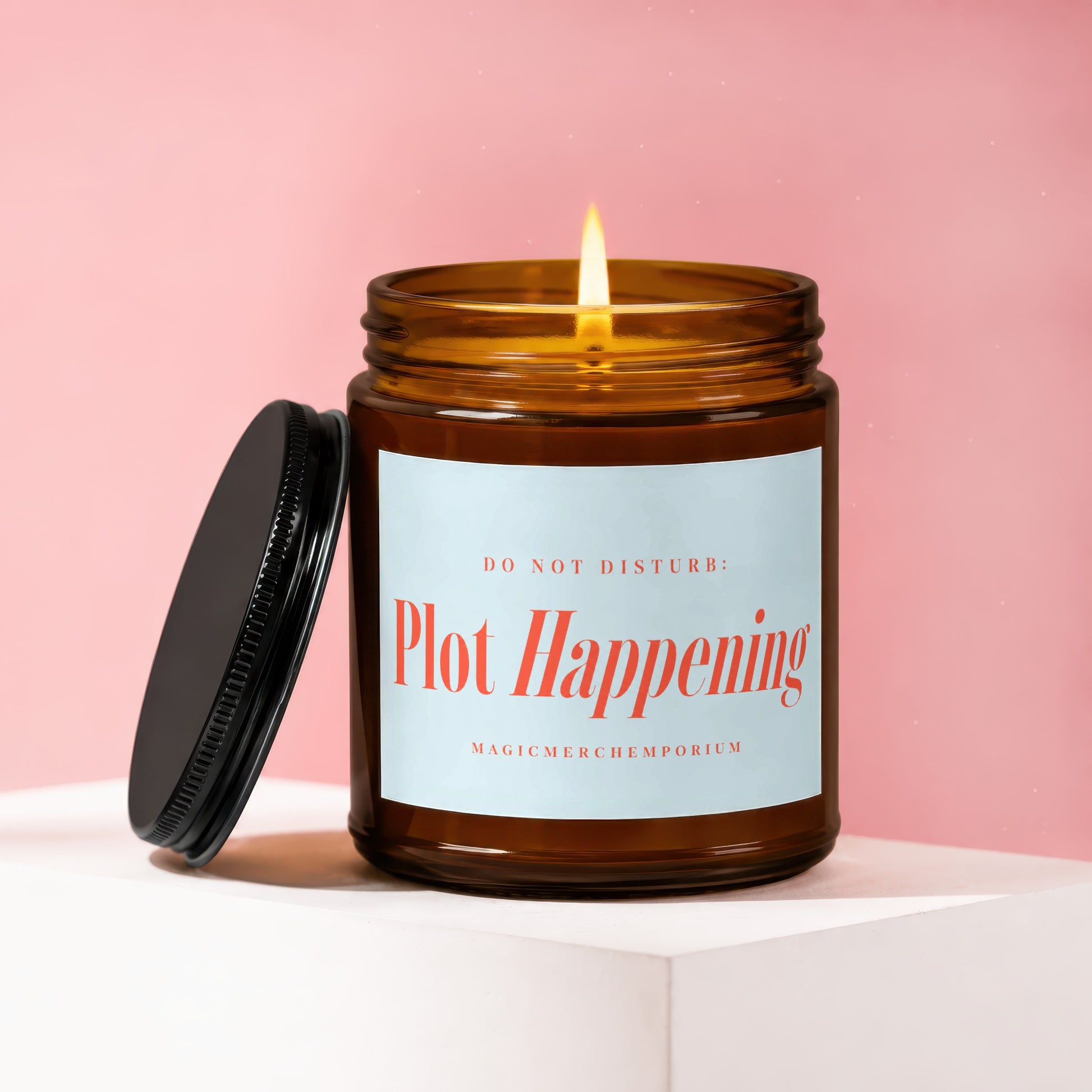 Amber jar candle with lit wick, "DO NOT DISTURB: Plot Happening" on label.